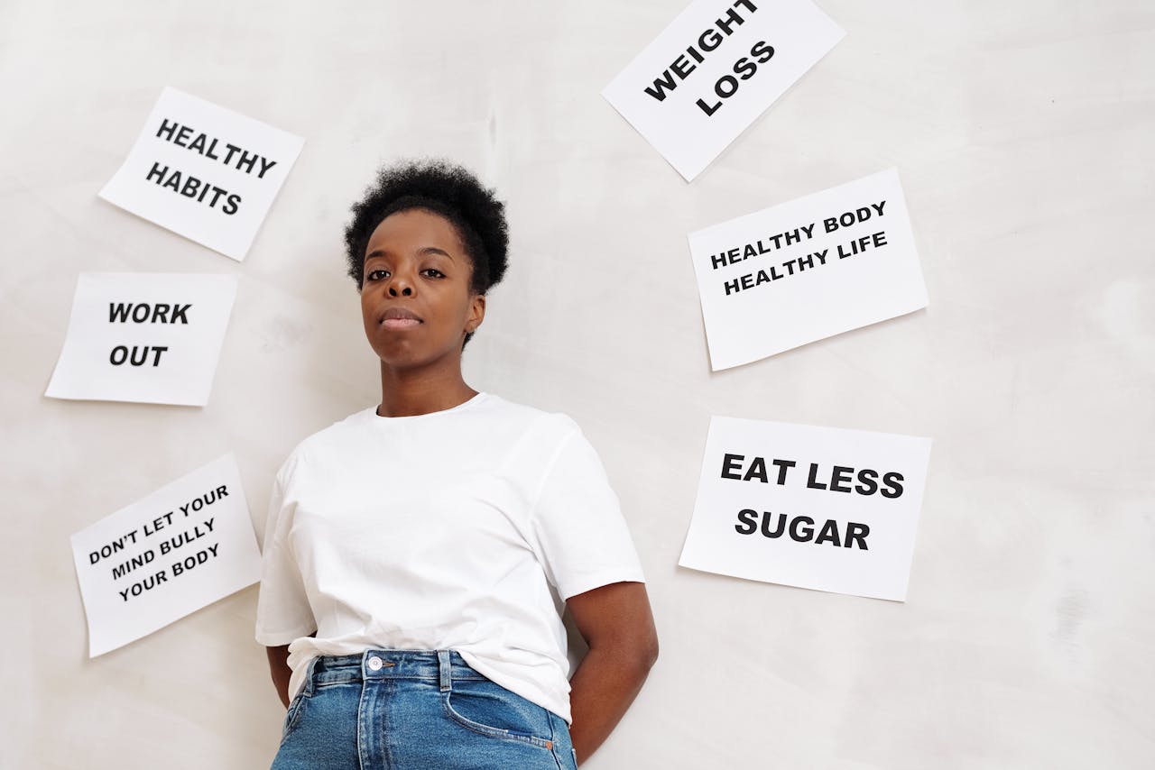 African American woman stands near motivational health slogans on the wall, promoting a positive lifestyle.